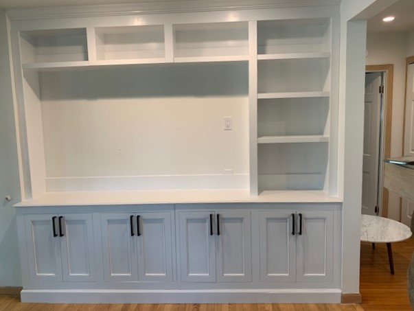 Empty white color shelves and cupboard below in a room with yellow lightning